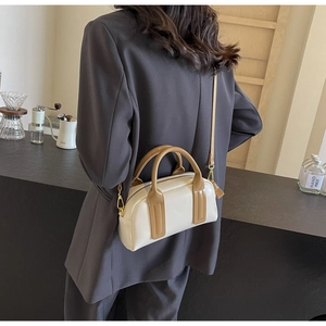Detail of a beige Boston bag with brown straps styled on a grey blazer model