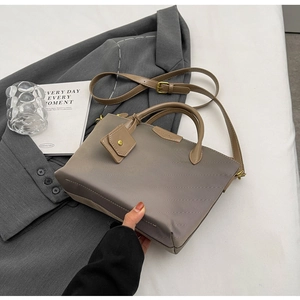 Detail of khaki textured fabric tote bag with golden hardware and GLEAMING branding