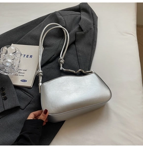 Detail of silver metallic bag featuring wavy edge design and decorative metal bar