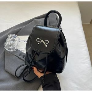 Glossy black mini backpack with silver metal bow detail and drawstring closure
