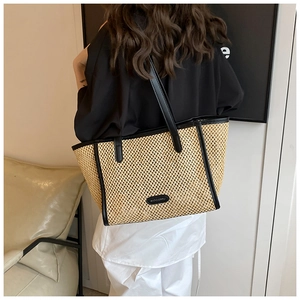 Détail du sac cabas en paille tissé à la main avec anses en cuir noir sur mannequin