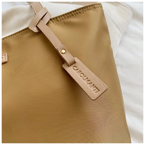 Macro detail of khaki oxford fabric with lychee leather trim and metal rivets