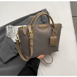 Close-up of taupe oxford tote bag with leather straps and CLEAR UX metal logo detail