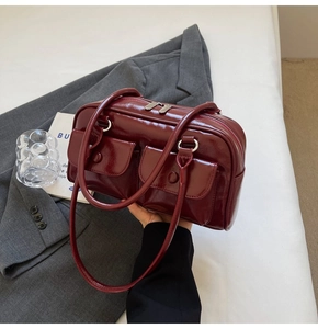 Vue détaillée du sac à main en cuir verni bordeaux avec deux poches à boucle