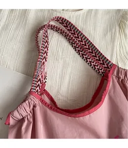 Detail der rosa Tragetasche mit gewebtem Riemen und plissiertem Nylon-Verschluss