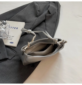 Detail view of silver crossbody bag with knotted strap and internal zipper pocket