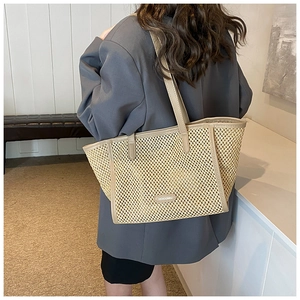 Détail d'un sac cabas en paille tressée avec garniture en cuir et bandoulière