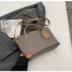 Detail of khaki tote bag showing fine texture, golden button charm and adjustable strap