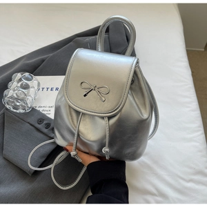 Close-up of a silver metallic mini backpack featuring a stylish bow and drawstring closure