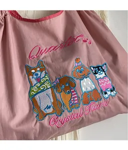 Nahaufnahme der rosa Tragetasche mit detailreicher Stickerei verschiedener Hunderassen