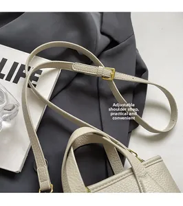 Detail of cream lychee texture leather bucket bag with adjustable gold-tone buckle strap