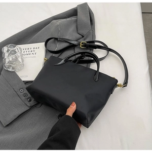Detailed view of black nylon tote bag with dual handles and metal buckle shoulder strap