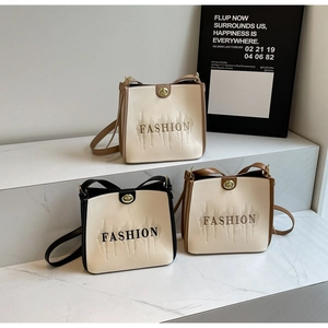 Three minimalist crossbody bucket bags with metal locks and FASHION logo on marble display