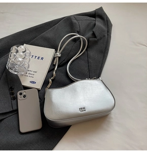 Close-up of a silver metallic hobo bag with unique wave strap and COIN ZDN branding