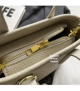 Close-up of golden metal zipper and texture on beige lychee leather handbag