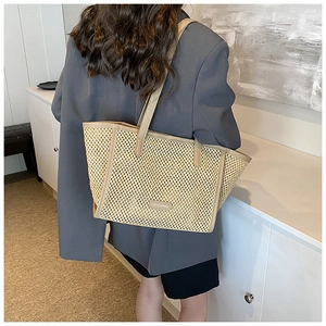 Gros plan détaillé montrant la texture du grand sac fourre-tout en paille tissée