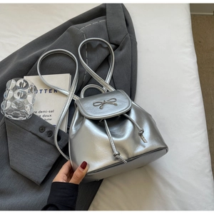 Detail of silver mini bucket backpack featuring metallic bow and drawstring closure