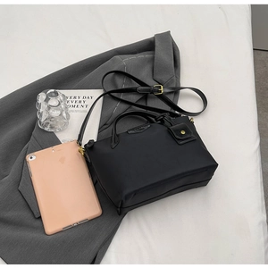 Detail of waterproof black nylon tote bag with adjustable strap on a grey blazer