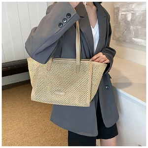 Détail du sac cabas en paille tressée avec bordure en cuir contrasté et écusson HOCOMU