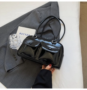 Gros plan d'un sac en cuir verni noir brillant avec deux poches à rabat et boucles en métal