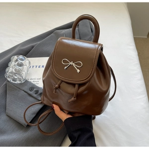 Detailed view of deep brown mini backpack with silver bow and drawstring closure