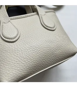 Detail of lychee pattern leather and neat stitching on beige bucket handbag strap