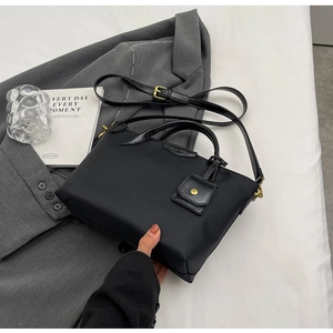 Detail of black waterproof Oxford tote bag featuring gold hardware and a small hanging pouch