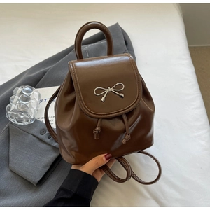 Close-up of brown PU leather mini backpack with silver metal bow and drawstring detail