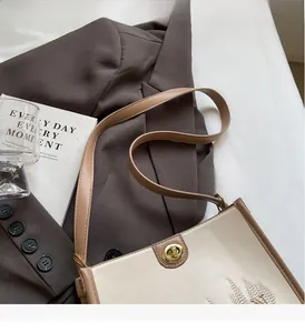 Detail of cream tote bag featuring urban embroidery and a vintage gold metal twist lock