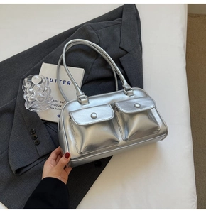 Détail du sac argenté brillant avec deux poches avant et rivets sur une veste grise