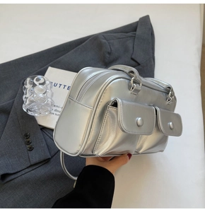 Sac Boston métallisé argenté avec poches avant présenté sur un élégant blazer gris