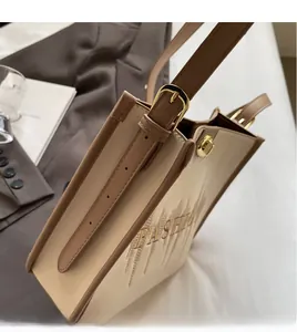 Detail of adjustable brown strap and golden buckle on two-tone fashion tote bag