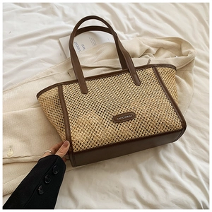 Détail du sac de plage en paille tissée avec poignées en cuir marron et logo de marque