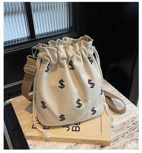 Détails du sac seau en toile beige avec broderie signe dollar et bandoulière réglable