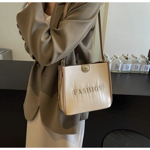 Detail view of beige tote bag showing golden twist lock and fashion wave embroidery