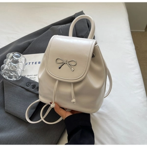 Detail of a white mini backpack with silver metal bow and delicate drawstring closure