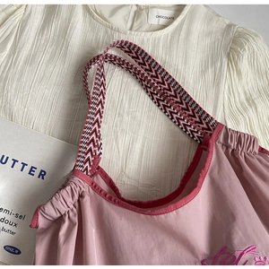 Detail der rosa Kordelzug-Tasche mit gewebtem Riemen und Stickerei-Verzierung