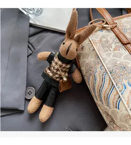 Detailed close-up of a brown knitted rabbit charm with houndstooth vest and gold clip