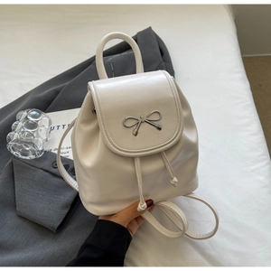 Detail of cream white PU leather mini backpack with silver metal bow and drawstring