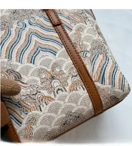Close-up of jacquard woven bucket bag showing intricate blue wave patterns and leather trim