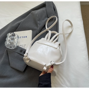 Detailed view of a white PU leather mini backpack with metal buckle and slim straps