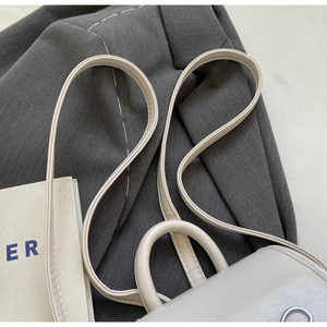 Detail of white patent leather backpack with round handle and metallic hardware