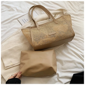 Détail d'un sac cabas en paille tressée avec anses en cuir et pochette sur tissu blanc