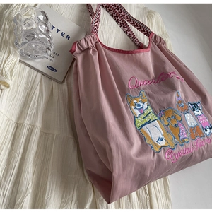 Detail der rosa Stofftragetasche mit bunten gestickten Hunden und gewebten Griffen