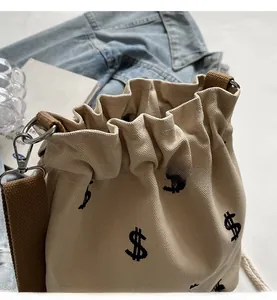 Détail du sac seau en toile avec imprimés dollar et fermeture à cordon
