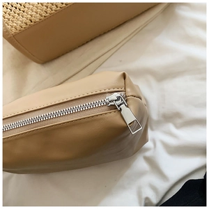 Détail de la fermeture éclair en métal argenté et texture en similicuir beige lisse
