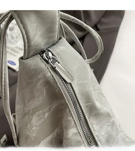 Detail of smooth silver zipper and marble pattern texture on a pleated shoulder bag