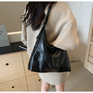 Detail of a black patchwork leather hobo bag with a chunky chain and adjustable strap