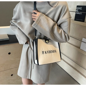 Detail view of the cream and black crossbody tote bag with FASHION print and twist lock