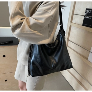 Detail of retro black leather tote bag with unique stitching and metal chain strap
